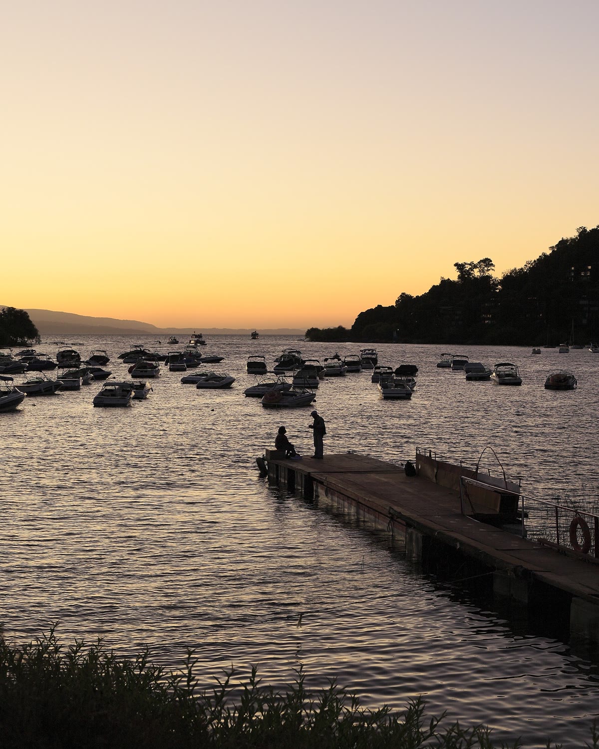 Atardecer sobre la bahía de Pucón, con botes y un muelle